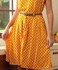 Woman wearing mustard yellow polka dot skirt with pockets and braided belt