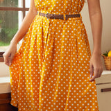Woman wearing mustard yellow polka dot skirt with pockets and braided belt