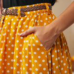 Close-up of yellow polka dot skirt with braided belt and functional side pocket