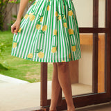 Woman wearing a green and white striped skirt with lemon patterns outdoors.