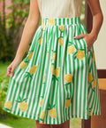 Green and white striped skirt with lemon pattern worn by a woman standing outdoors.