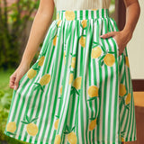 Green and white striped skirt with lemon pattern worn by a woman standing outdoors.