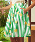 Green and white striped skirt with lemon pattern worn by a woman with her hand in her skirt pocket