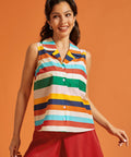 Woman wearing a retro rainbow striped sleeveless button-front top with a chest pocket.