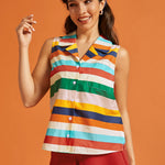 Woman wearing a sleeveless rainbow striped cotton blouse with a camp collar and chest pocket.