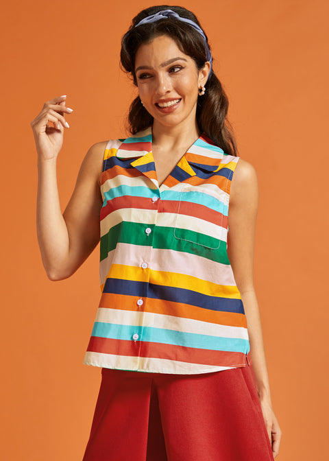Woman wearing a sleeveless rainbow striped cotton blouse with a camp collar and chest pocket.