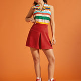 Woman wearing a colorful striped camp collar shirt tucked into a red skirt.
