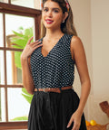 Woman wearing a black and white polka dot sleeveless blouse with button front detail