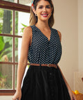 Woman wearing a black sleeveless blouse with white polka dots