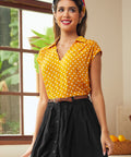 Woman wearing vintage-inspired yellow blouse with white polka dots