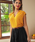Woman wearing yellow polka dot collared blouse with black skirt