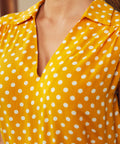 Close-up of golden yellow polka dot blouse with V-neck collar detail