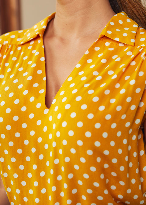 Close-up of golden yellow polka dot blouse with V-neck collar detail