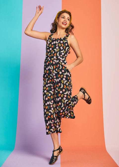 Woman jumping in novelty fruit print cropped jumpsuit