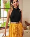 Woman wearing black tie-neck halter top with yellow polka dot skirt