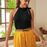 Woman wearing vintage-inspired black halter knit top with polka dot skirt
