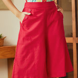 Woman wearing red skort skirt shorts with a colorful top in an indoor setting