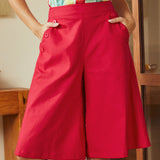 Person wearing a colorful top and red skort in an indoor setting