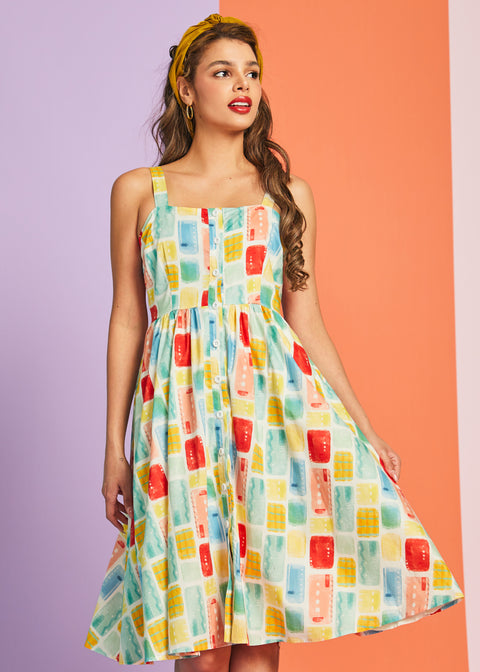 Woman modeling pastel watercolor print sundress with square neckline and button-front design