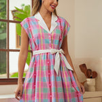 Woman wearing a colorful plaid vintage style dress in a kitchen setting