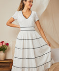 Womanwearing white midi dress with black ric rac trim, front view