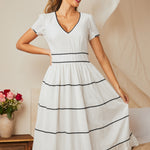 Womanwearing white midi dress with black ric rac trim, front view