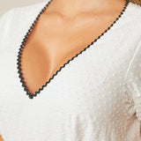Close-up of white dress V-neckline with black ric rac trim detail