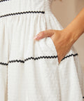 Close-up of textured fabric white cotton dress with ric rac trim and pockets