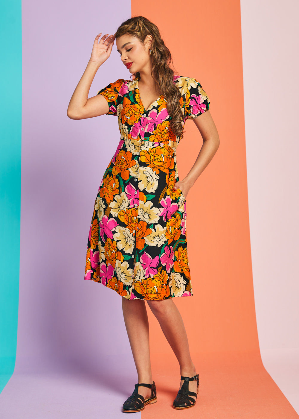 Woman wearing colorful retro black floral midi dress with puff sleeves and pockets
