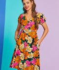 Woman wearing a colorful floral dress against a gradient background