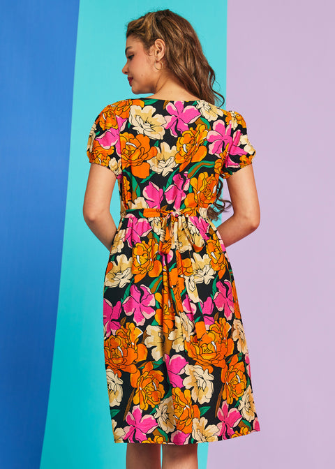 Back view of bright orange and hot pink floral midi dress with waist tie detail