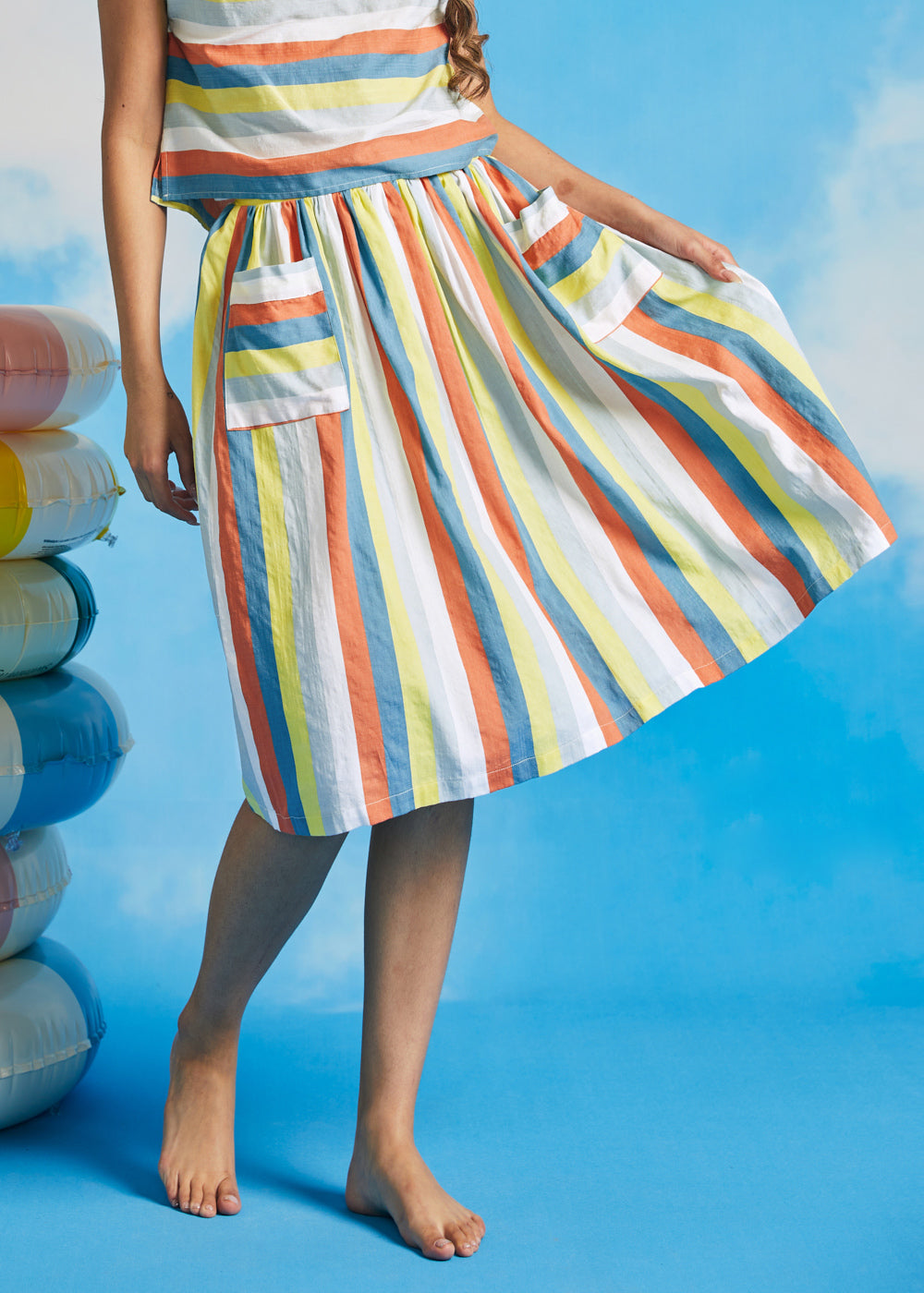 Woman twirling in retro-inspired multicolor stripe dirndl skirt with full gathered silhouette