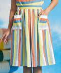 Woman wearing vintage-inspired pastel stripe dirndl skirt with oversized patch pockets and sleeveless striped top
