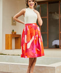 Woman in a colorful midi skirt standing outdoors near a pool