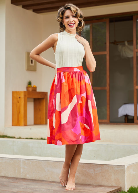 Woman in a colorful midi skirt standing outdoors near a pool