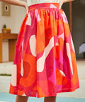 Close-up of skirt fabric showing bold abstract pink, orange, and red pattern