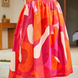 Close-up of skirt fabric showing bold abstract pink, orange, and red pattern