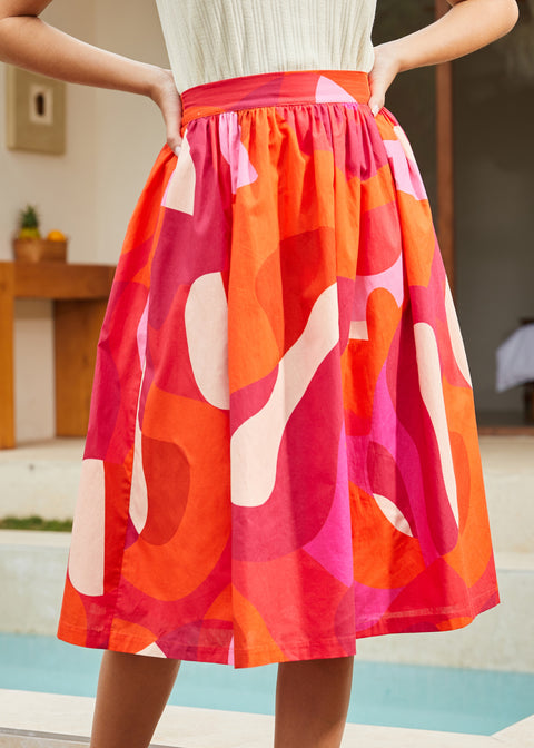 Close-up of skirt fabric showing bold abstract pink, orange, and red pattern
