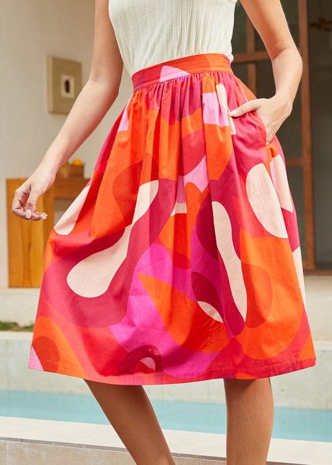 Person wearing a colorful skirt with abstract patterns by a poolside.