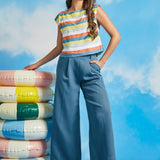 Woman wearing vintage-inspired pastel stripe boatneck top with wide-leg blue trousers
