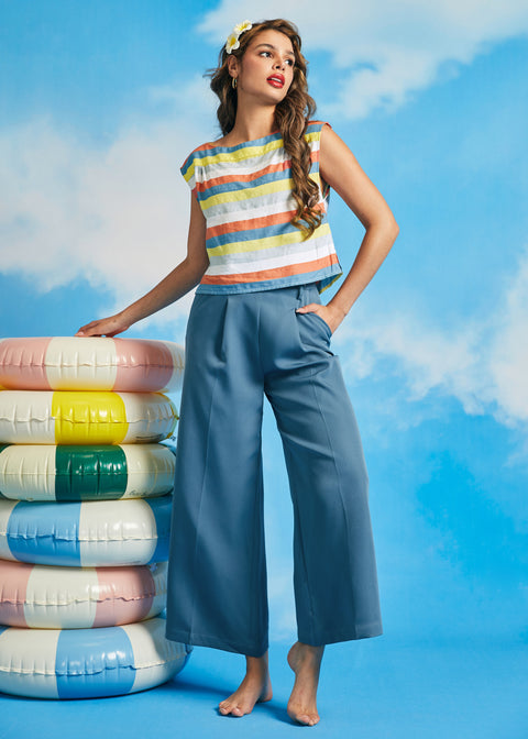 Woman wearing vintage-inspired pastel stripe boatneck top with wide-leg blue trousers