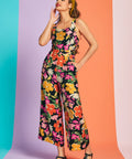Woman wearing black floral jumpsuit with cropped wide legs and retro-inspired print