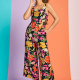 Woman wearing black floral jumpsuit with cropped wide legs and retro-inspired print