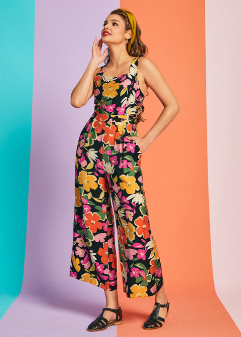 Woman wearing black floral jumpsuit with cropped wide legs and retro-inspired print