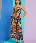 Woman wearing sleeveless tropical floral jumpsuit with pockets and square neckline