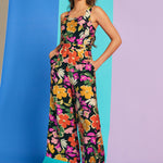 Woman wearing sleeveless tropical floral jumpsuit with pockets and square neckline