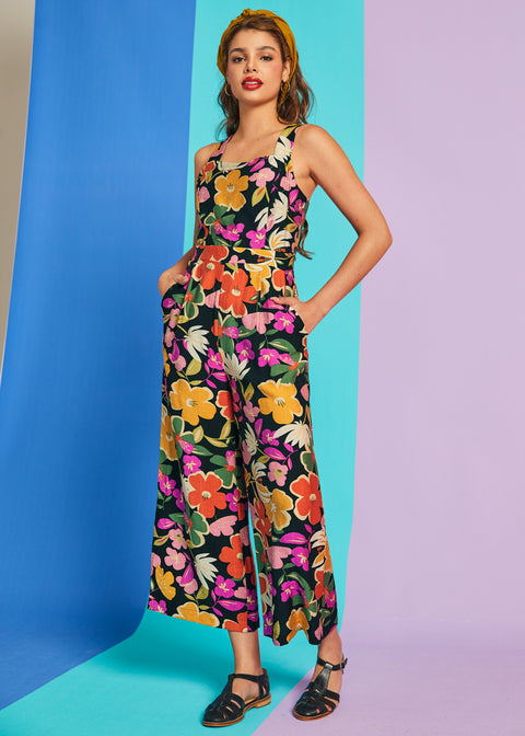 Woman wearing sleeveless tropical floral jumpsuit with pockets and square neckline
