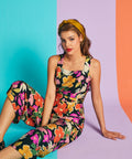 Woman sitting in colorful floral cropped jumpsuit with square neckline and wide-leg fit