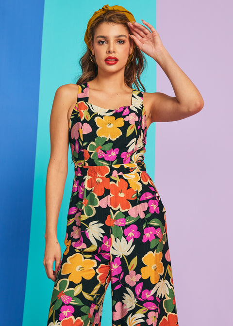 Woman posing in colorful floral jumpsuit with square neckline and relaxed fit