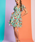 Woman wearing aqua fruit print wrap mini dress with flutter sleeves and tie waist